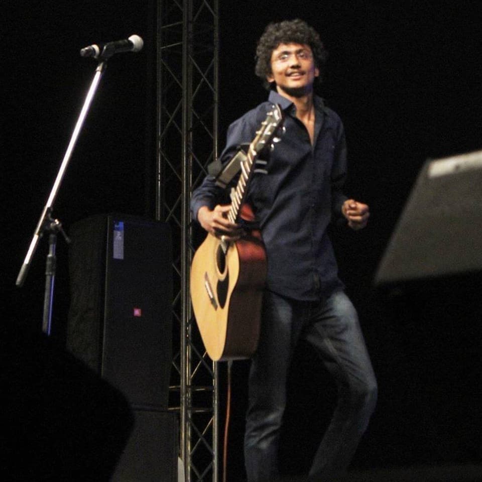 Ronak Bhatt singing on stage with an acoustic guitar